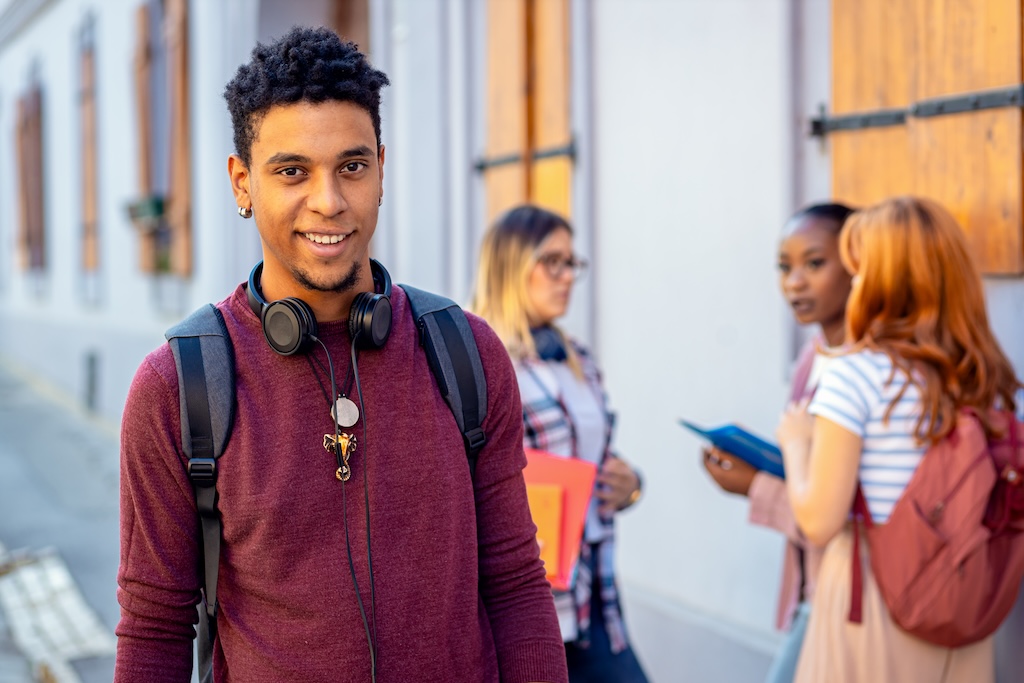 jeune-etudiant-souriant-devant-un-etablissement-scolaire